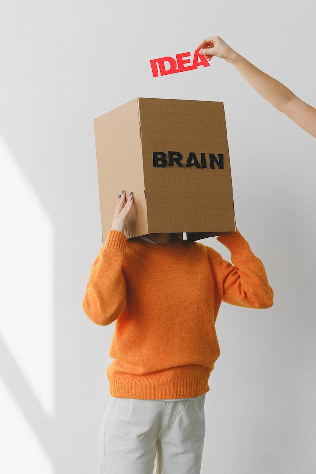 Kuvassa on ihminen, jolla on laatikko päässsään. Laatikossa lukee brain ja laatikkoon laitetaan ideoita.